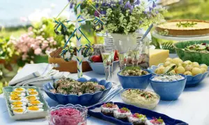 En härlig midsommar buffe med sill, potatis, ägg och en paj. En midsommarstång i bakgrunden.