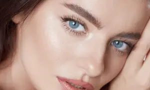 Närbild på en kvinna med blå ögon och perfekt makeup. Hennes ögonbryn ger en illusion av ett "brow lift".