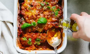 En ugnsbakad auberginegratäng med tomatsås och ost, toppad med färska örter. En perfekt idé för ett utsökt aubergine recept.