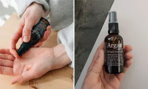 Händer applicerar arganolja hår för glans och näring. Flaskan med ekologisk kallpressad arganolja visas.