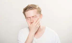 Man med slutna ögon och hand över munnen, kan vara ett tecken på l-lysin brist symtom som trötthet eller svaghet.