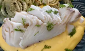 Läckert vit fisk serverad med krämig sås och ugnsbakad fänkål, garnerad med dill.