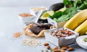 En härlig samling av magnesiumrik mat: bönor, mandlar, mörk choklad, bananer, spenat, avokado och frön.