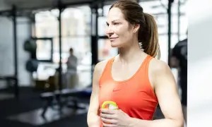 Kvinna med axelpress muskler i gym, håller en vattenflaska.
