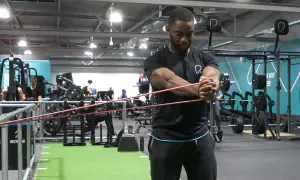 Man utför pallof press med gummiband i ett gym.