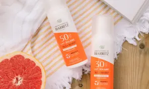 Två solkrämer från Biarritz med naturliga ingredienser, en med SPF 50 och en med SPF 30, ligger bredvid en grapefrukt och en bok.