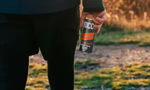 Person in athletic wear holding a NOCCO FOCUS energy drink can outdoors.