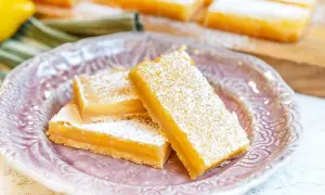 Citronkaka i långpanna, pudrad med florsocker, serveras på en vacker lila tallrik. Perfekt för fikat!