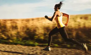Kvinna springer i hög fart på en grusväg, en del av ett intensivt hiit pass.