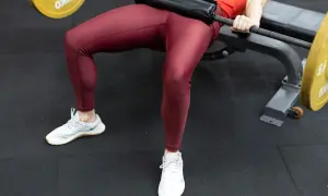 En person utför hip thrust med en skivstång på en bänk.