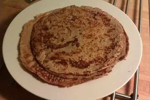 En hög med gyllenbruna proteinpannkakor på en vit tallrik. Perfekt för ett snabbt och näringsrikt proteinpannkakor recept.