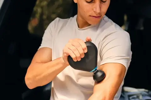 En man använder en Rubicson massagepistol mini för att massera sin arm.