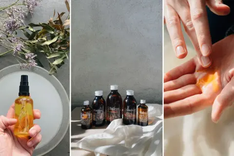 En hand håller en flaska med gyllene olja, bredvid torkade blommor. Flera mörkbruna flaskor med hudvårdsprodukter står uppradade. En droppe olja, som pro mandelolja, sprids ut i en handflata.