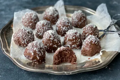 Chokladiga havrebollar med kokos på ett silverfat. Ett perfekt recept för hemmagjorda godsaker.