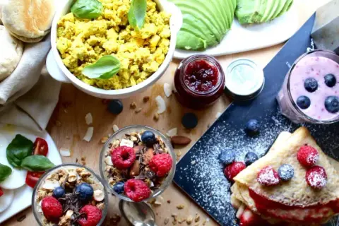 En härlig vegansk frukost med pannkakor, smoothies, granola, tofu scramble och färska bär.