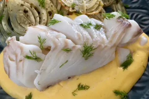 Läckert vit fisk serverad med krämig sås och ugnsbakad fänkål, garnerad med dill.