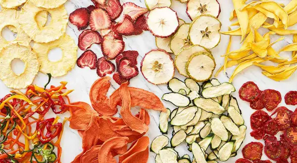 En färgsprakande samling av torkad frukt och grönsaker, som ananasringar, jordgubbar, äppelskivor, mango, paprika, aprikoser, zucchini och tomater. Ett nyttigt snacks!