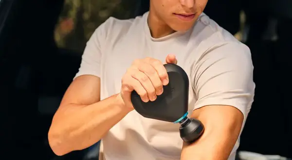 En man använder en Rubicson massagepistol mini för att massera sin arm.