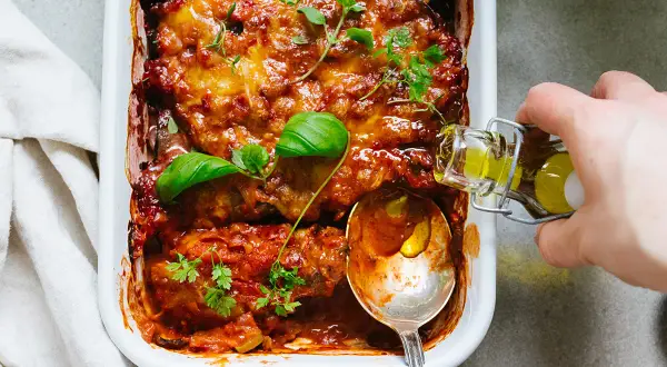 En ugnsbakad auberginegratäng med tomatsås och ost, toppad med färska örter. En perfekt idé för ett utsökt aubergine recept.