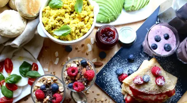 En härlig vegansk frukost med pannkakor, smoothies, granola, tofu scramble och färska bär.