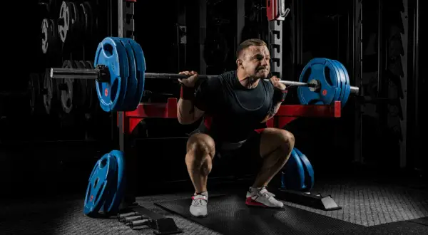 Man gör tunga squats svenska i gym.