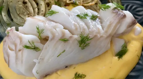Läckert vit fisk serverad med krämig sås och ugnsbakad fänkål, garnerad med dill.