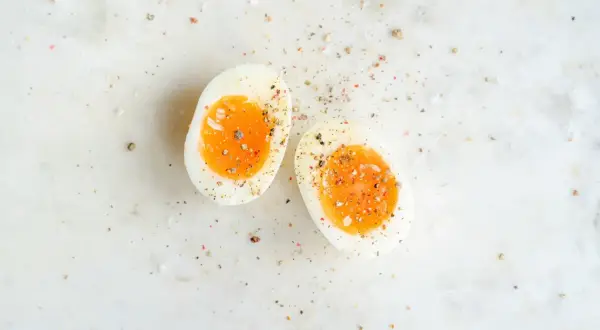 Två halvor av ett mjukkokt ägg med en krämig gula, strödda med salt och peppar. Helt ärligt äggpulver kan vara en bra ersättning när färska ägg inte finns till hands.
