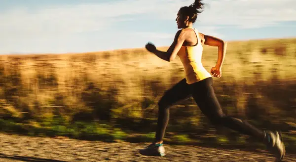 Kvinna springer i hög fart på en grusväg, en del av ett intensivt hiit pass.