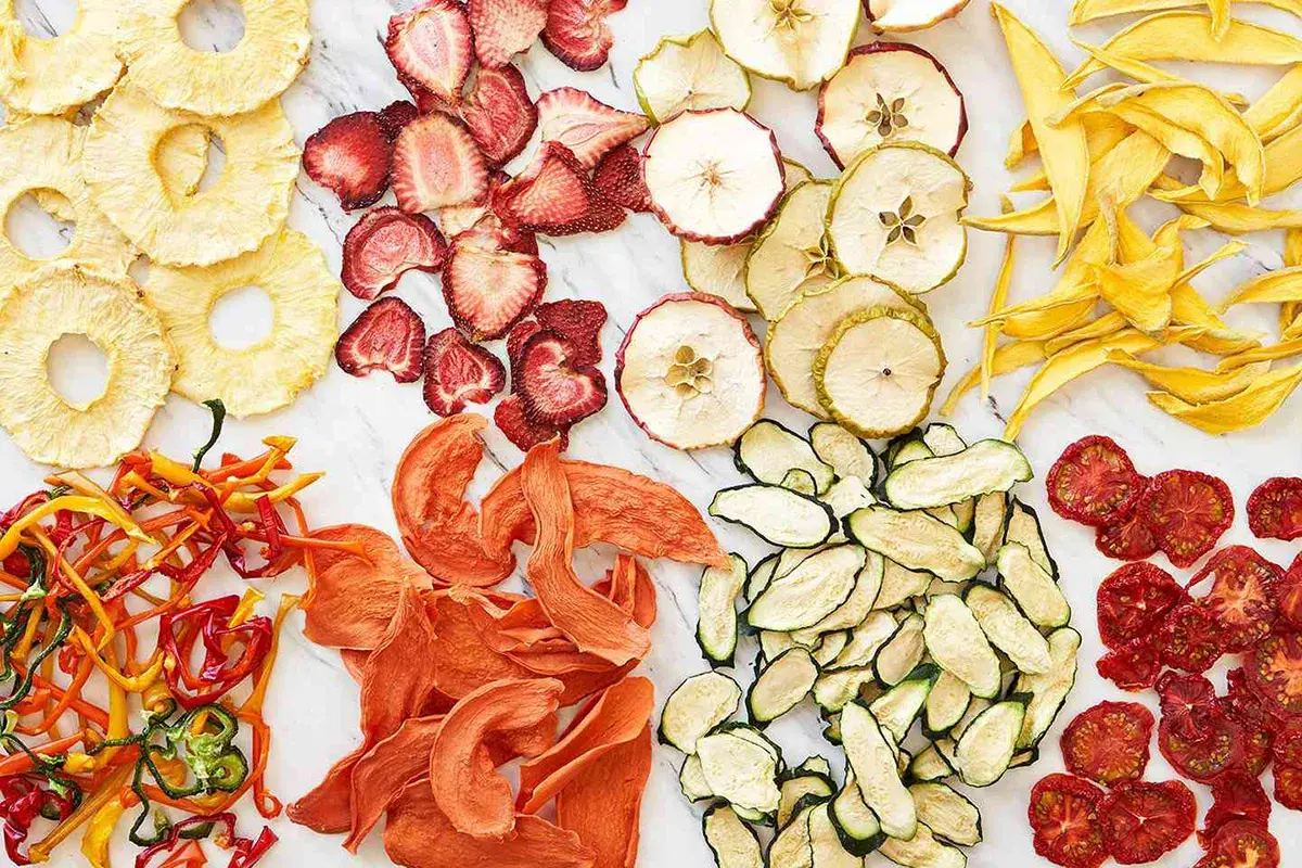 En färgsprakande samling av torkad frukt och grönsaker, som ananasringar, jordgubbar, äppelskivor, mango, paprika, aprikoser, zucchini och tomater. Ett nyttigt snacks!
