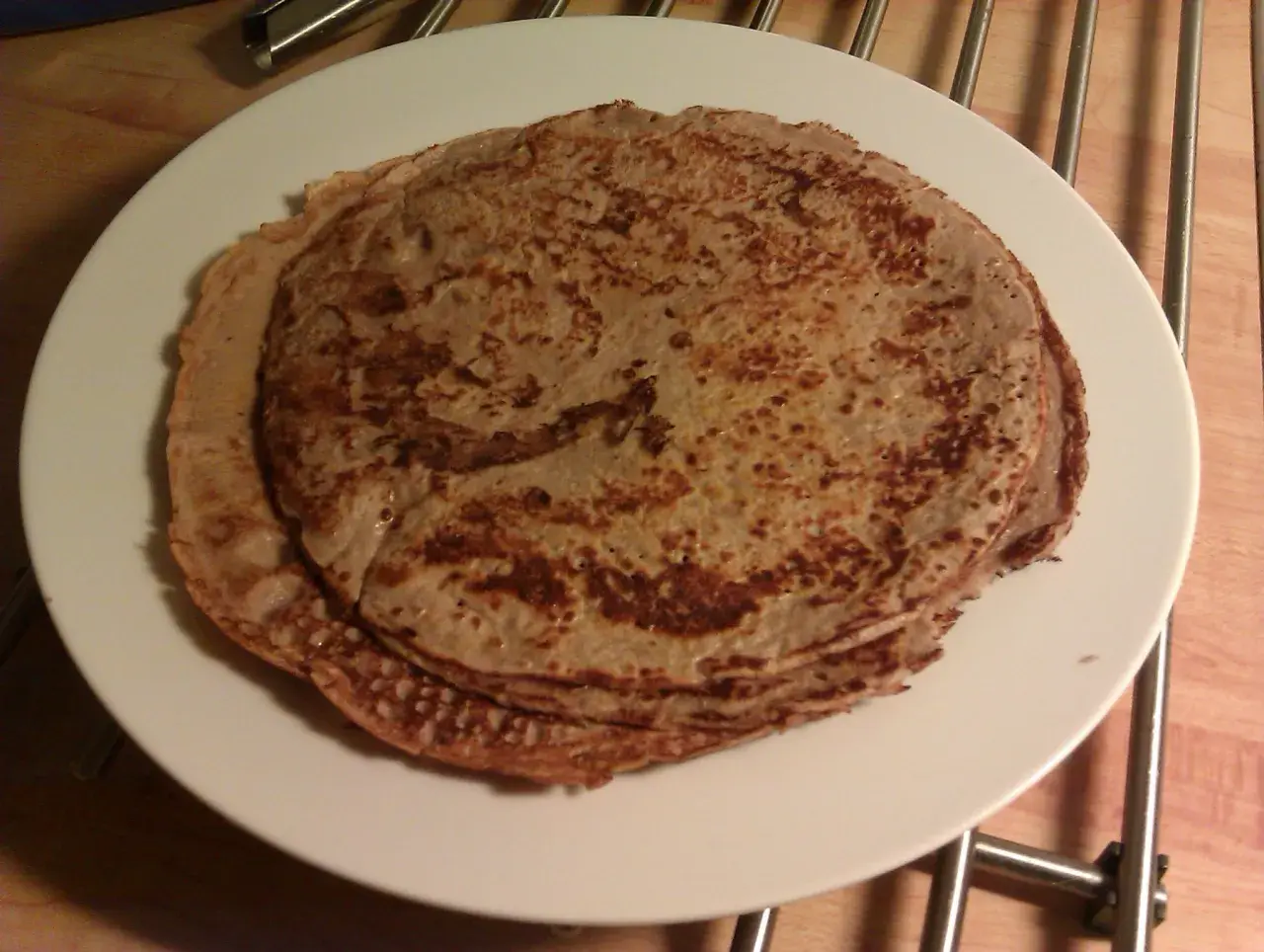 En hög med gyllenbruna proteinpannkakor på en vit tallrik. Perfekt för ett snabbt och näringsrikt proteinpannkakor recept.