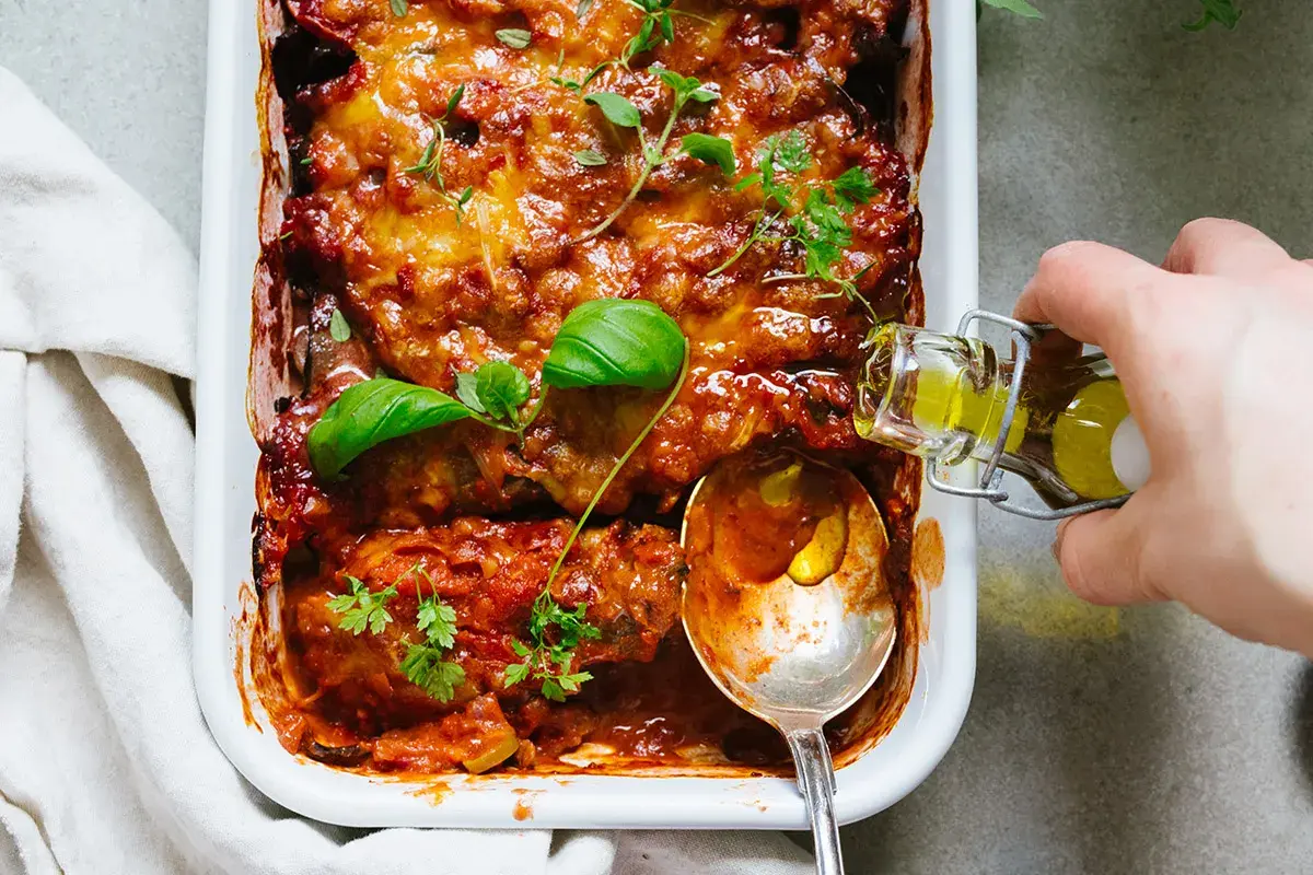 En ugnsbakad auberginegratäng med tomatsås och ost, toppad med färska örter. En perfekt idé för ett utsökt aubergine recept.
