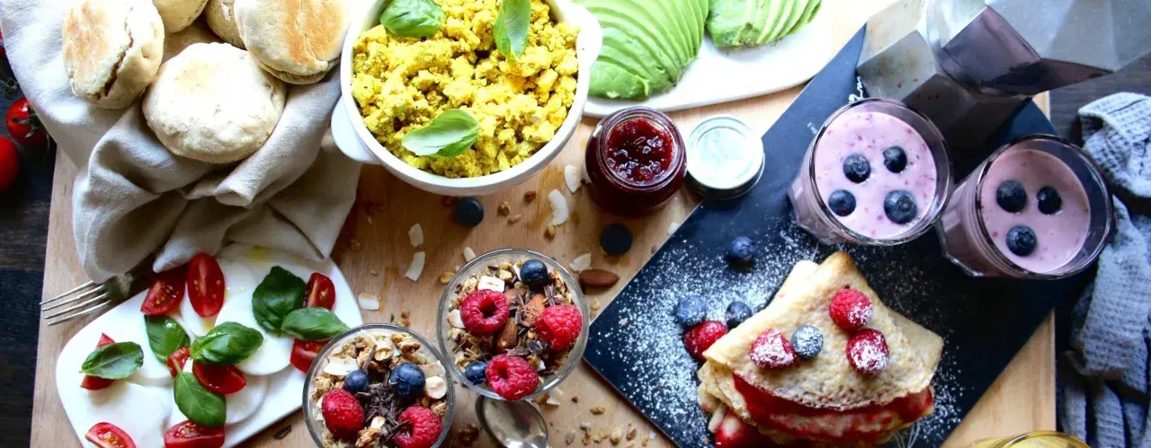 En härlig vegansk frukost med pannkakor, smoothies, granola, tofu scramble och färska bär.