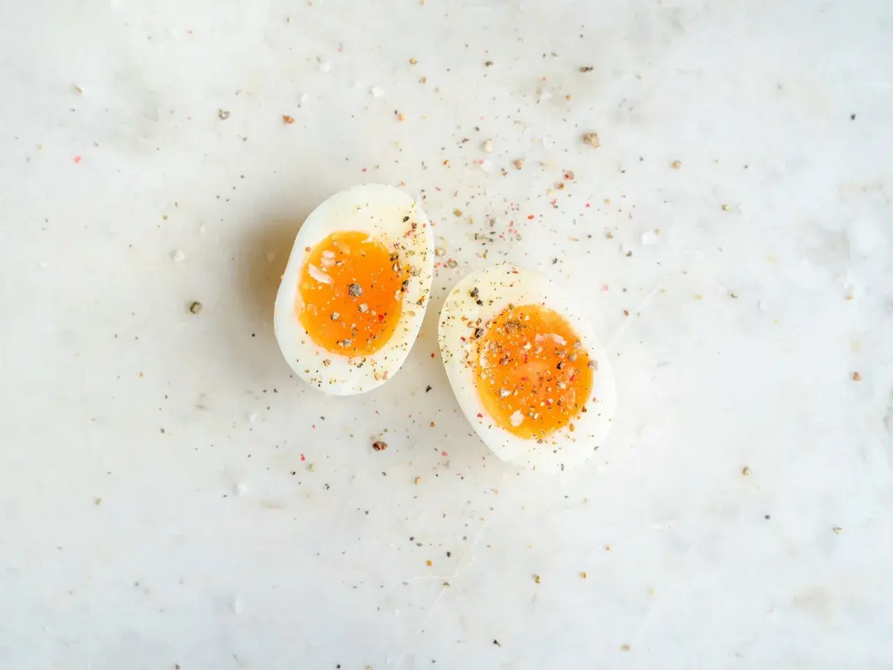 Två halvor av ett mjukkokt ägg med en krämig gula, strödda med salt och peppar. Helt ärligt äggpulver kan vara en bra ersättning när färska ägg inte finns till hands.