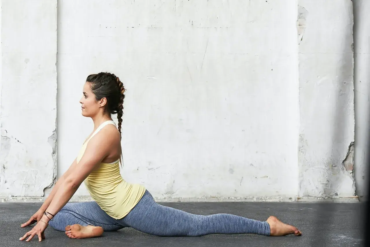 Kvinna i duvan yoga-position mot en sliten vägg.