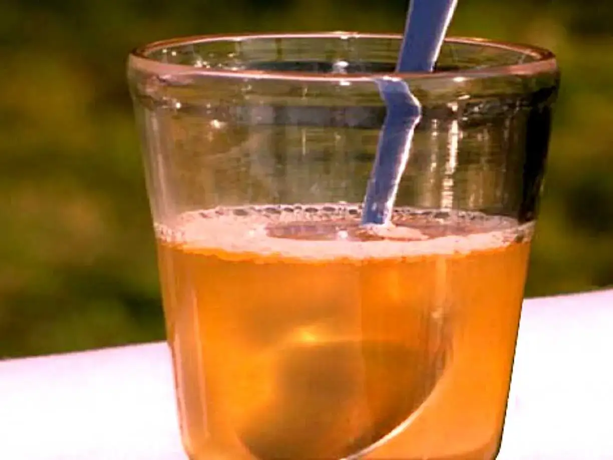 Ett glas med gyllene dryck och en bl&aring; sked. Kanske en h&auml;lsodryck med honung nyttigt f&ouml;r kroppen.