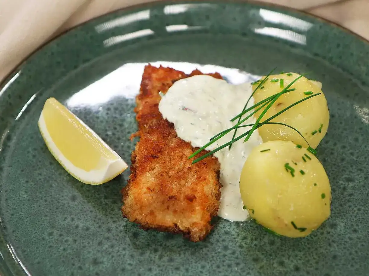 Panerad torsk med dillmajonn&auml;s, kokt potatis och citronklyfta p&aring; en gr&ouml;n tallrik. En klassisk svensk r&auml;tt.