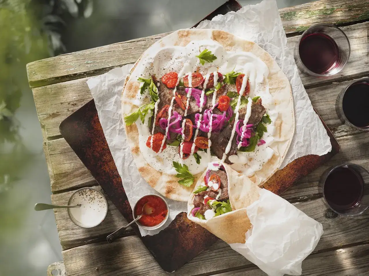 En h&auml;rlig kebab p&aring; ett lantligt bord, perfekt f&ouml;r ett somrigt kebab recept. Serveras med r&ouml;da tomater, l&ouml;k och vit s&aring;s.