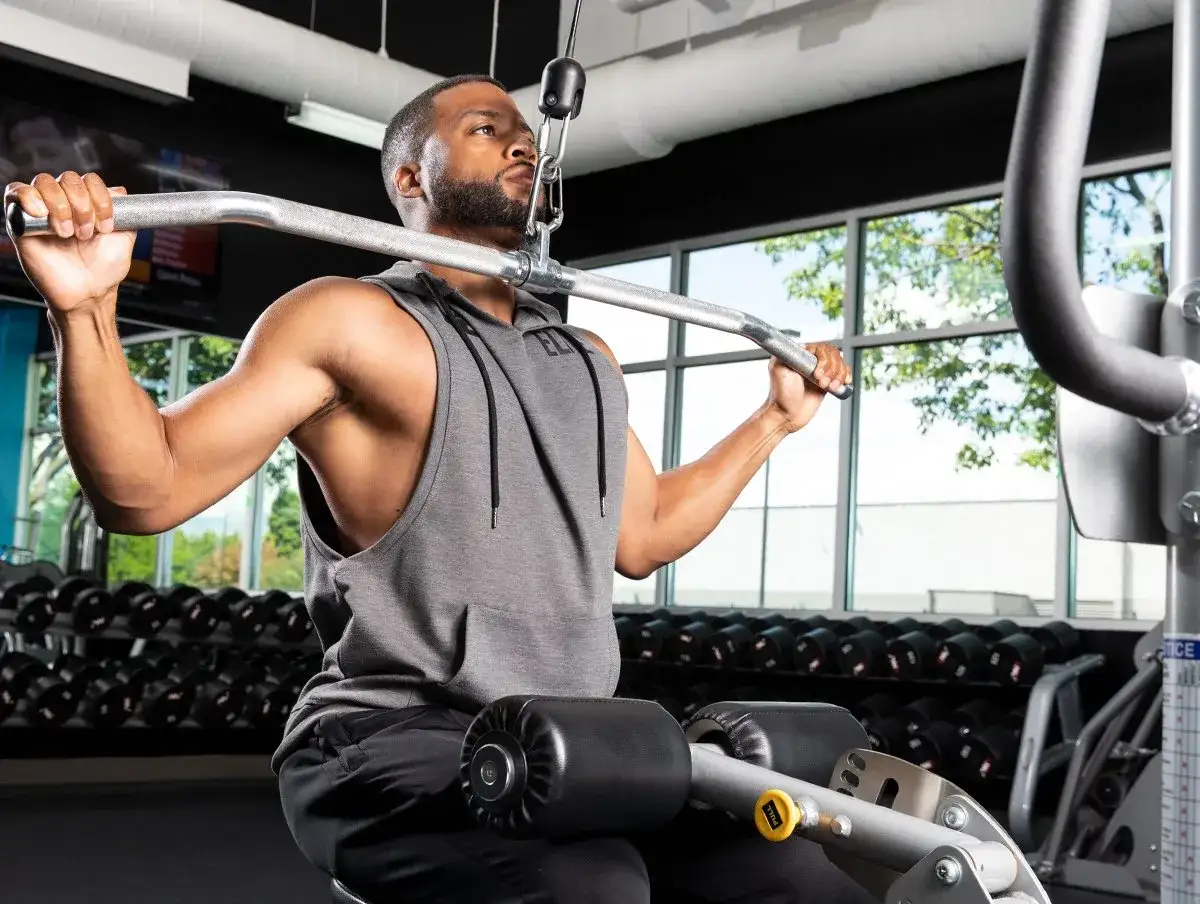 Man tränar ryggpass på gym med latsdrag.