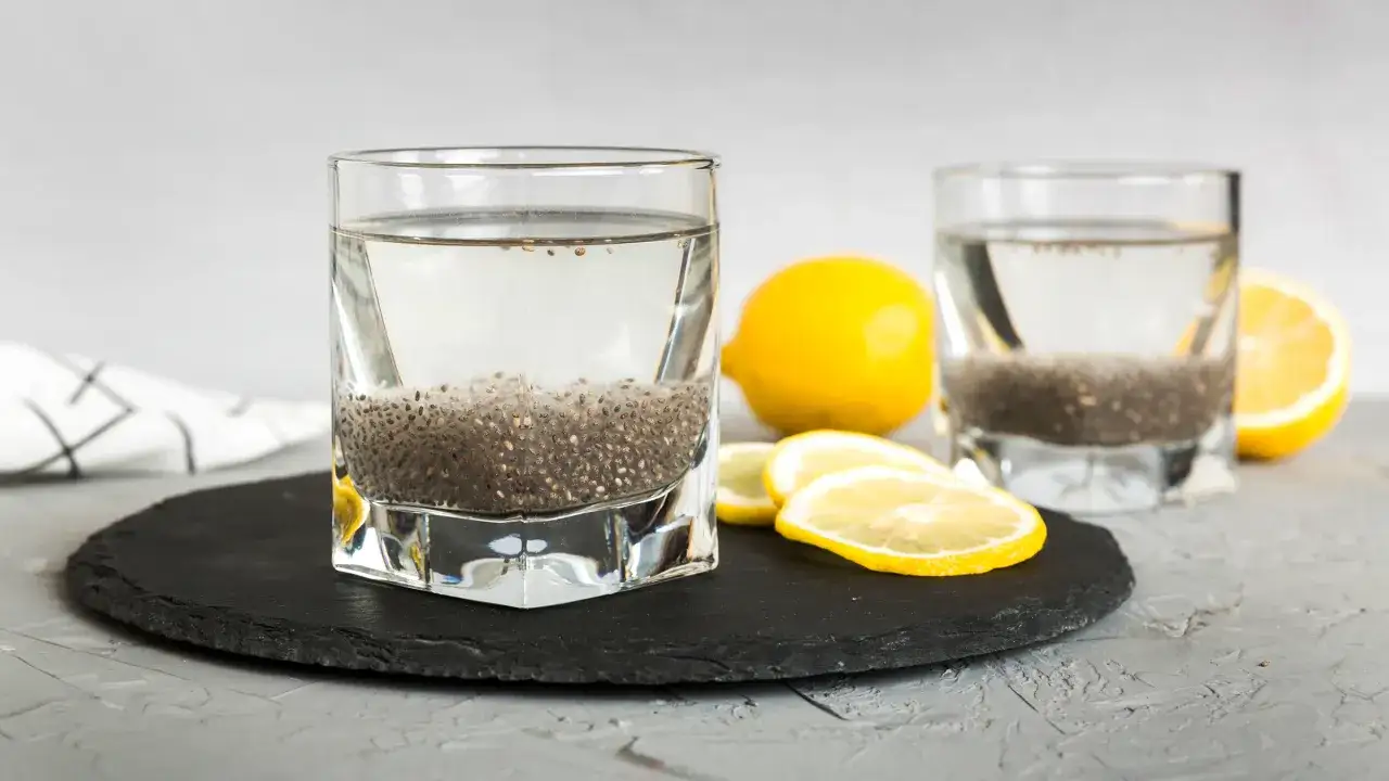 Tv&aring; glas med chia vatten st&aring;r p&aring; en svart skifferplatta. Citroner ligger bredvid.