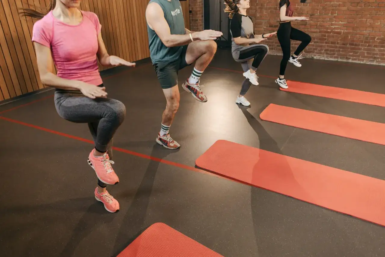 Personer utf&ouml;r h&ouml;ga kn&auml;n under ett intensivt hiit pass i ett gym.