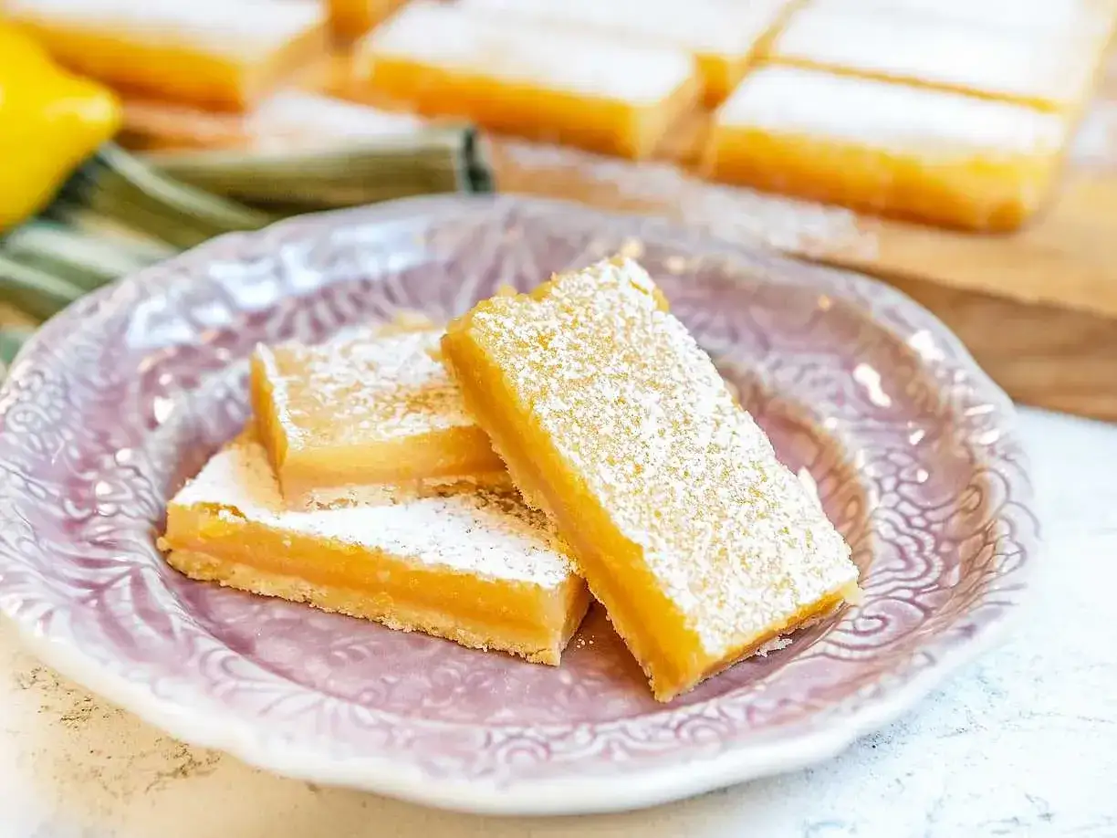 Citronkaka i långpanna, pudrad med florsocker, serveras på en vacker lila tallrik. En perfekt syrlig och söt godsak.