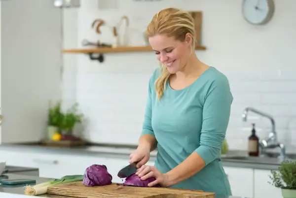 Kvinna hackar rödkål i köket, en del av en antiinflammatorisk kost som kan inkludera potatis.