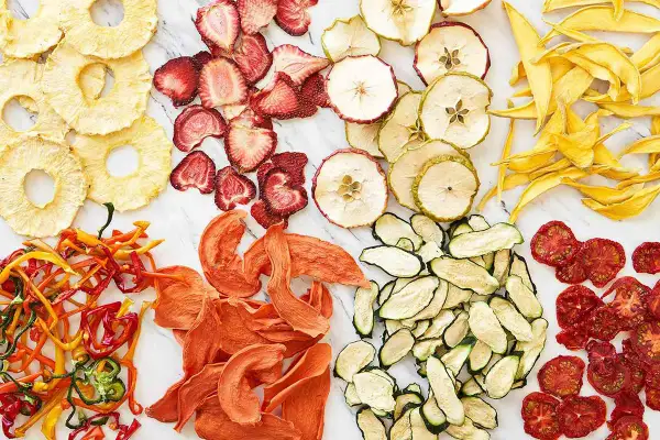 En färgsprakande samling av torkad frukt och grönsaker, som ananasringar, jordgubbar, äppelskivor, mango, paprika, aprikoser, zucchini och tomater. Ett nyttigt snacks!