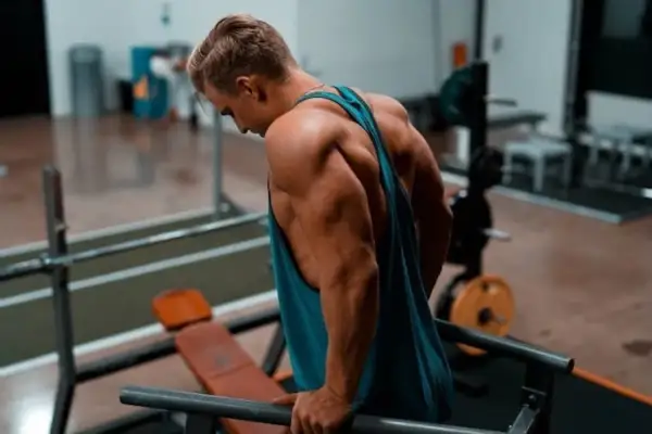 Man tränar dips, hans triceps muskler syns tydligt.