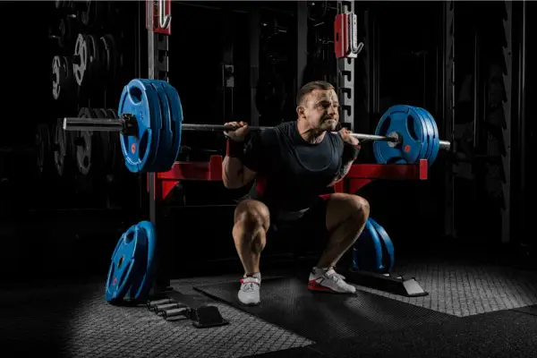 Man gör tunga squats svenska i gym.