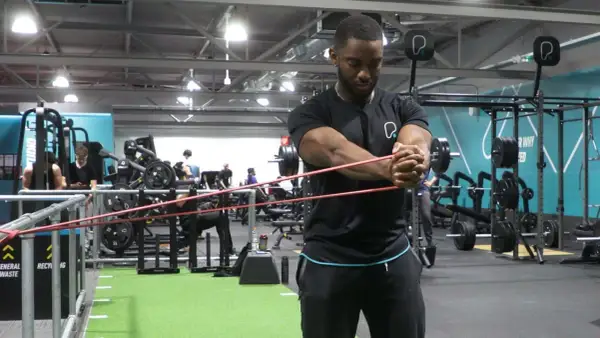 Man utför pallof press med gummiband i ett gym.