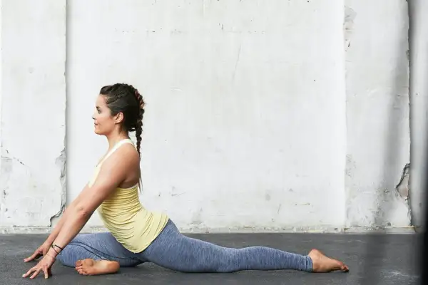 Kvinna i duvan yoga-position mot en sliten vägg.