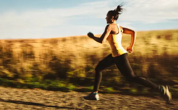 Kvinna springer i hög fart på en grusväg, en del av ett intensivt hiit pass.